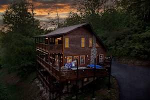 This stunning three-story cabin offers a classic log cabin feel with expansive wraparound decks, cozy lighting, and a peaceful wooded setting. Exterior Pingpong table, fire pit dinning table and more