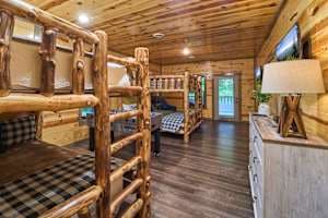This spacious bunk room features two queen-over-queen log bunk beds, a foosball table, and deck access. Enjoy a private bathroom, closet, and rustic cabin charm, perfect for families and groups. A cozy and fun retreat for kids and adults alike!
