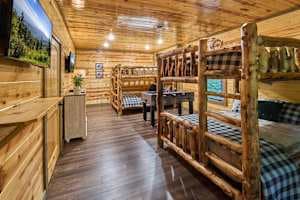 This spacious bunk room features two queen-over-queen log bunk beds, a foosball table, and deck access. Enjoy a private bathroom, closet, and rustic cabin charm, perfect for families and groups. A cozy and fun retreat for kids and adults alike!