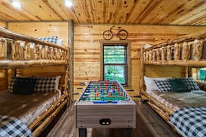 This spacious bunk room features two queen-over-queen log bunk beds, a foosball table, and deck access. Enjoy a private bathroom, closet, and rustic cabin charm, perfect for families and groups. A cozy and fun retreat for kids and adults alike!
