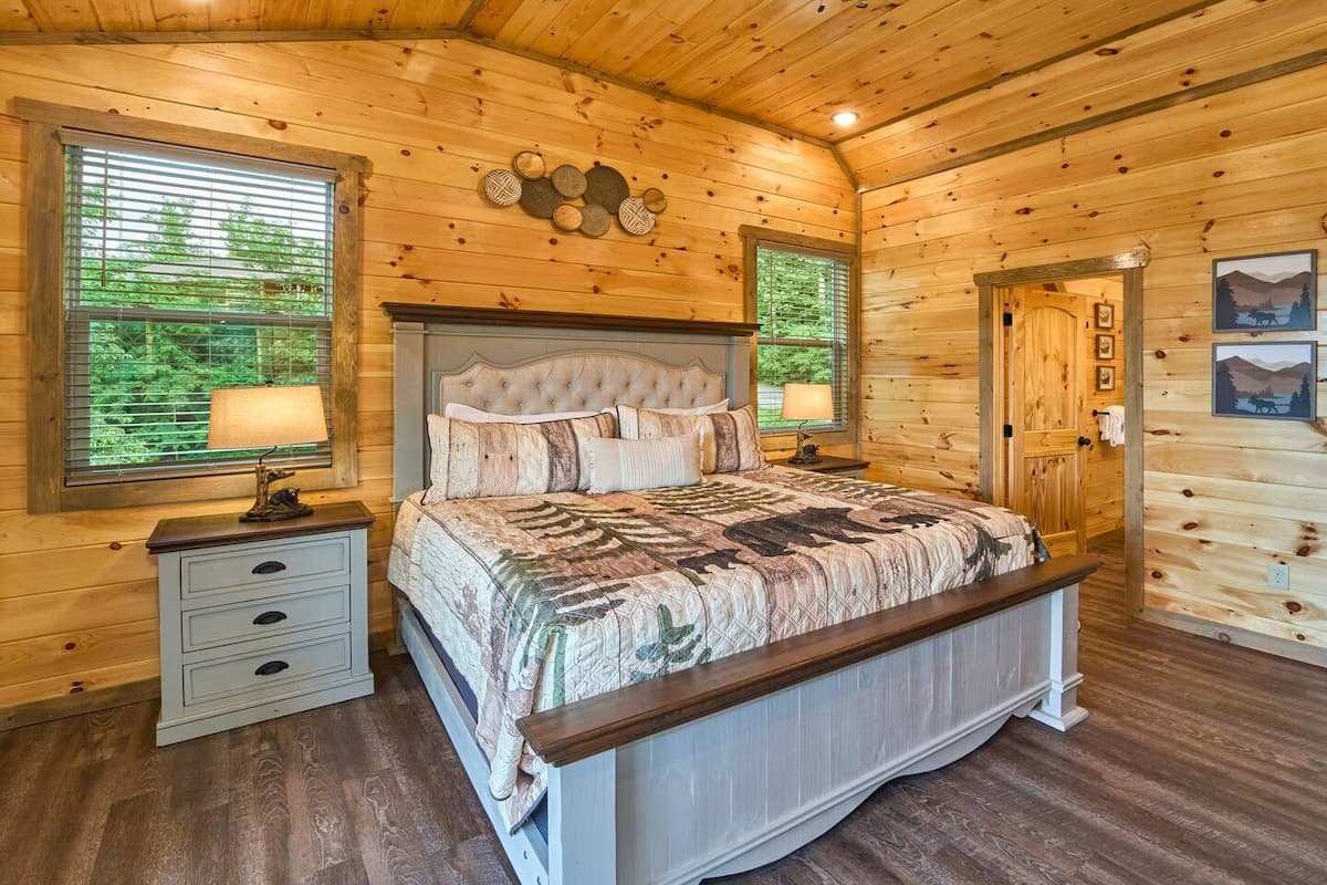 Escape to this cozy bedroom with a king-size bed, private bathroom, closet, dresser, and TV. Step onto the deck to enjoy stunning views and fresh mountain air. Designed for comfort and relaxation, this serene retreat is perfect after a long day.
