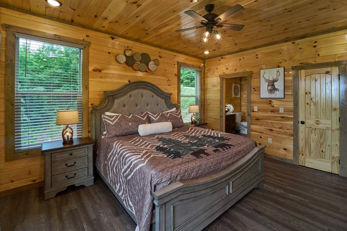 Escape to this cozy bedroom with a king-size bed, private bathroom, closet, dresser, and TV. Step onto the deck to enjoy stunning views and fresh mountain air. Designed for comfort and relaxation, this serene retreat is perfect after a long day.