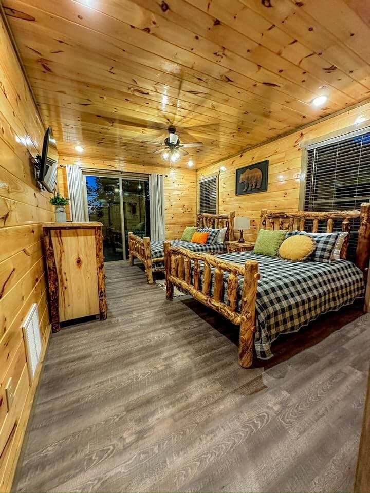 Cozy rustic bedroom featuring handcrafted log beds, warm wood interiors, and a private balcony access. Enjoy the perfect blend of comfort and cabin charm, ideal for a peaceful night's sleep in the heart of the Smoky Mountains!