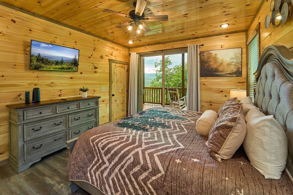 Escape to this cozy bedroom with a king-size bed, private bathroom, closet, dresser, and TV. Step onto the deck to enjoy stunning views and fresh mountain air. Designed for comfort and relaxation, this serene retreat is perfect after a long day.