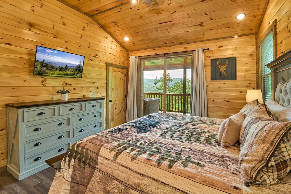 Escape to this cozy bedroom with a king-size bed, private bathroom, closet, dresser, and TV. Step onto the deck to enjoy stunning views and fresh mountain air. Designed for comfort and relaxation, this serene retreat is perfect after a long day.