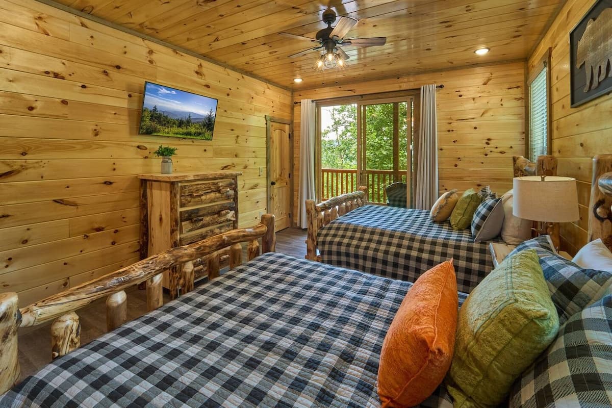 Cozy rustic bedroom featuring handcrafted log beds, warm wood interiors, and a private balcony access. Enjoy the perfect blend of comfort and cabin charm, ideal for a peaceful night's sleep in the heart of the Smoky Mountains!