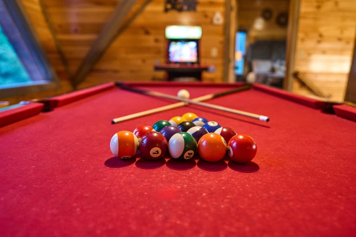 Challenge friends to a game of pool in this stylish loft game area with vaulted ceilings and scenic views. Featuring a cozy cabin atmosphere and classic arcade décor, it's the perfect space to relax, have fun, and enjoy friendly competition!