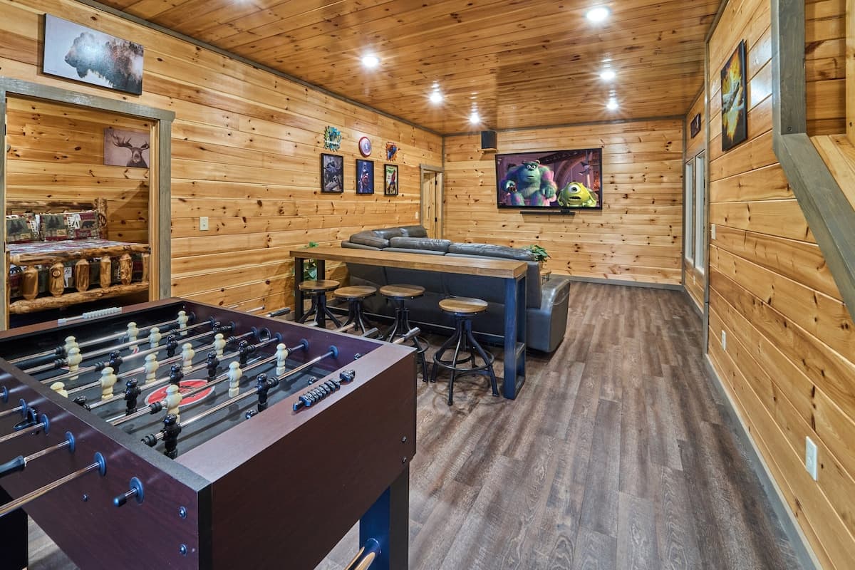 Enjoy a game of foosball in this cozy cabin space featuring two fireplaces for the perfect mix of fun and relaxation. With rustic charm and warm ambiance, this inviting area is great for friendly competition or unwinding by the fire after a long day!