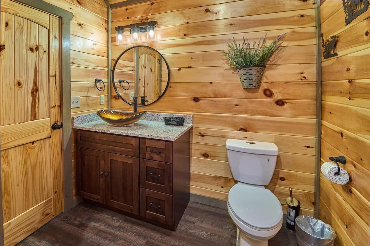 This full bathroom offers modern comfort with fresh towels, toilet paper, hand soap, body soap, and a hair dryer. Featuring a walk-in shower, granite vanity, and cozy cabin charm, it's stocked with essentials to ensure a refreshing & hassle-free stay