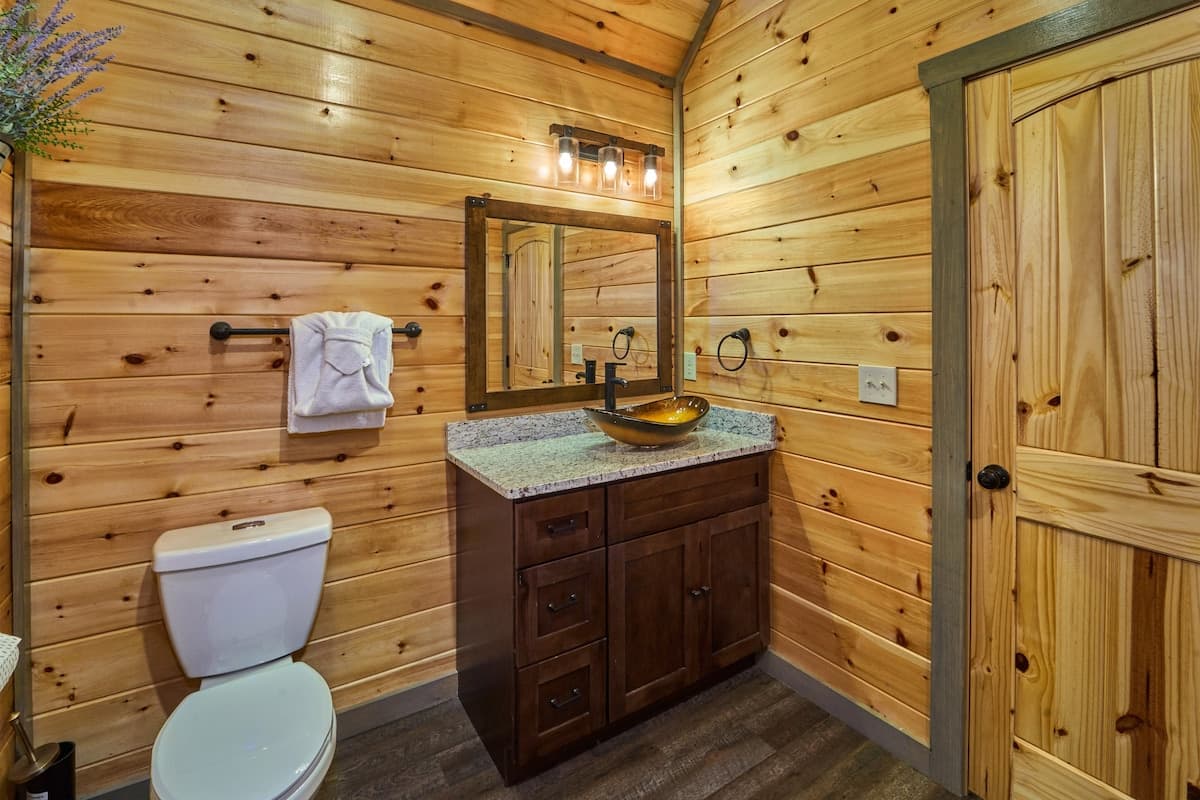 This full bathroom offers modern comfort with fresh towels, toilet paper, hand soap, body soap, and a hair dryer. Featuring a walk-in shower, granite vanity, and cozy cabin charm, it's stocked with essentials to ensure a refreshing & hassle-free stay