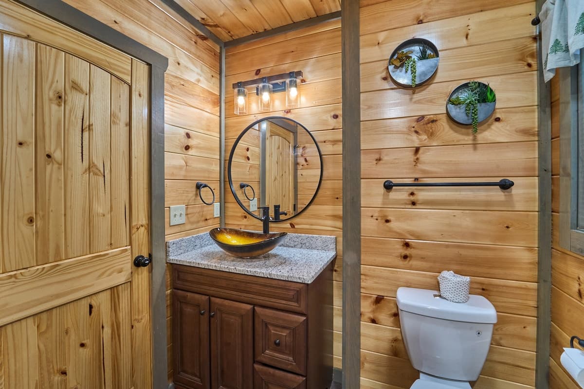 This full bathroom offers modern comfort with fresh towels, toilet paper, hand soap, body soap, and a hair dryer. Featuring a walk-in shower, granite vanity, and cozy cabin charm, it's stocked with essentials to ensure a refreshing & hassle-free stay
