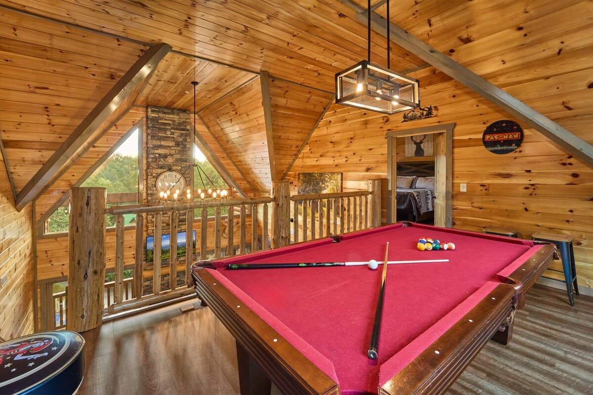 Challenge friends to a game of pool in this stylish loft game area with vaulted ceilings and scenic views. Featuring a cozy cabin atmosphere and classic arcade décor, it's the perfect space to relax, have fun, and enjoy friendly competition!