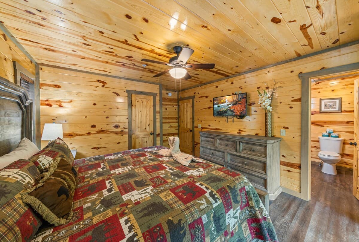 Relax in a spacious bedroom featuring a king-size bed, private bathroom, and closet. Step onto the deck for fresh air and nature views. With cozy cabin décor and modern amenities, this inviting retreat offers perfect blend of comfort and tranquility.