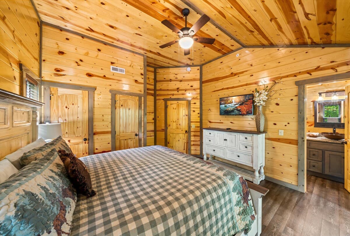 Escape to this cozy bedroom with a king-size bed, private bathroom, closet, dresser, and TV. Step onto the deck to enjoy stunning views and fresh mountain air. Designed for comfort and relaxation, this serene retreat is perfect after a long day.