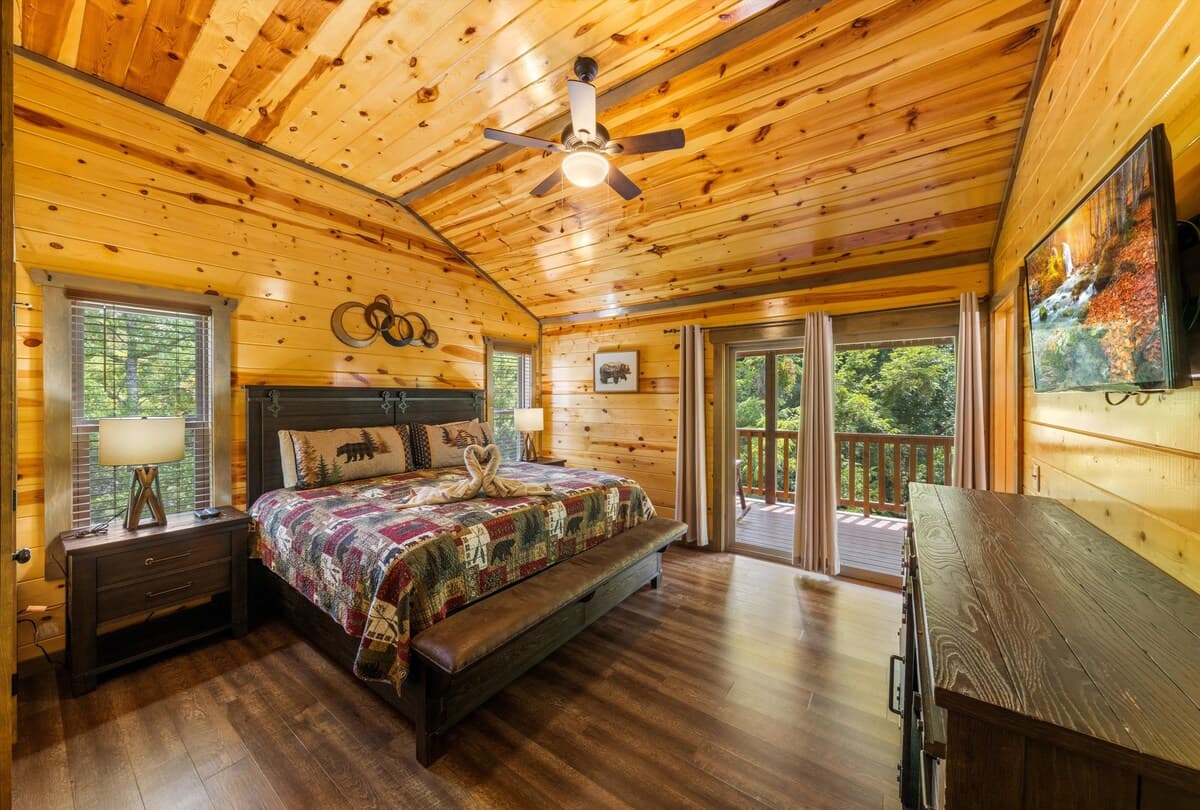 Escape to this cozy bedroom with a king-size bed, private bathroom, closet, dresser, and TV. Step onto the deck to enjoy stunning views and fresh mountain air. Designed for comfort and relaxation, this serene retreat is perfect after a long day.