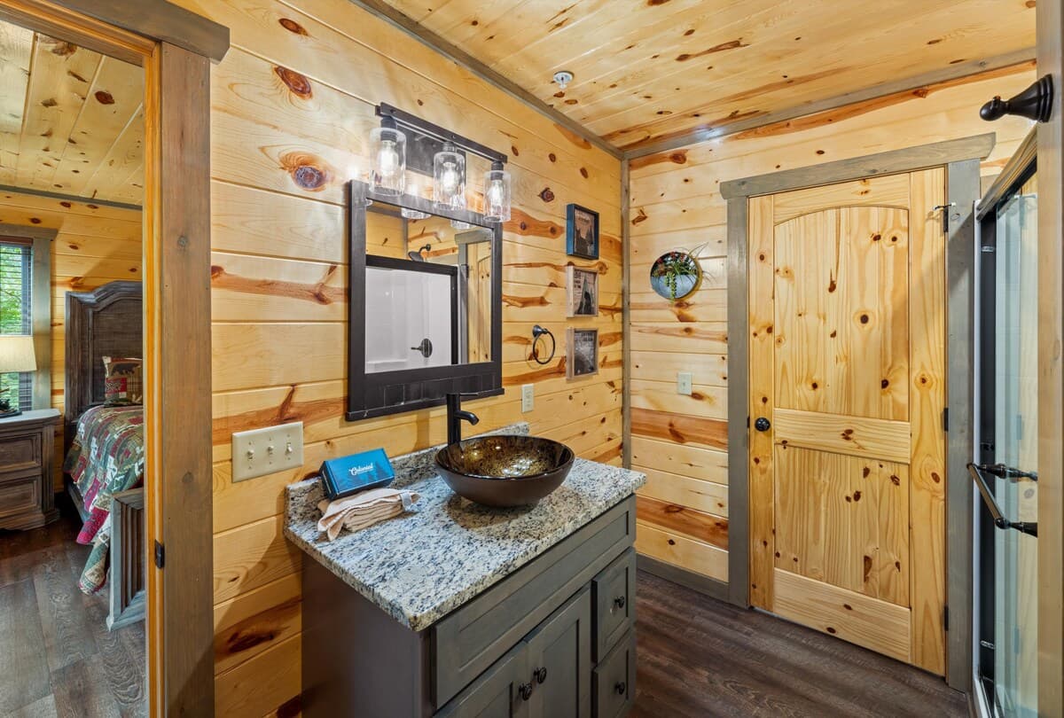 This full bathroom offers modern comfort with fresh towels, toilet paper, hand soap, body soap, and a hair dryer. Featuring a walk-in shower, granite vanity, and cozy cabin charm, it's stocked with essentials to ensure a refreshing & hassle-free stay