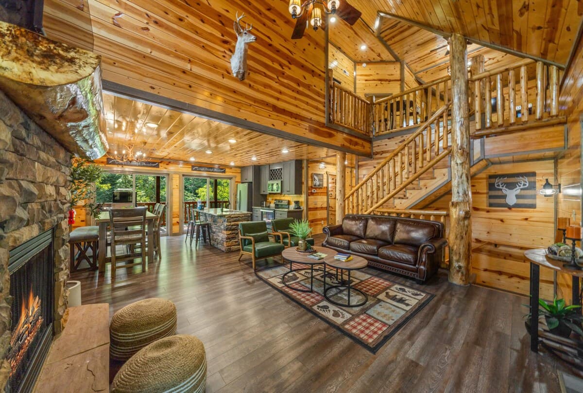 Unwind in this cozy cabin-style living room with vaulted wood ceilings, a stone gas fireplace, and scenic forest views! Enjoy plush seating and an open layout, perfect for families / groups. This rustic yet modern retreat offers warmth and comfort.